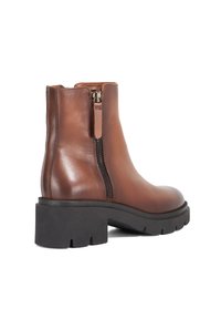 Brown leather ankle boot with a smooth texture, zip closure on the side, and a chunky black rubber sole. Curved shape and minimal detailing.