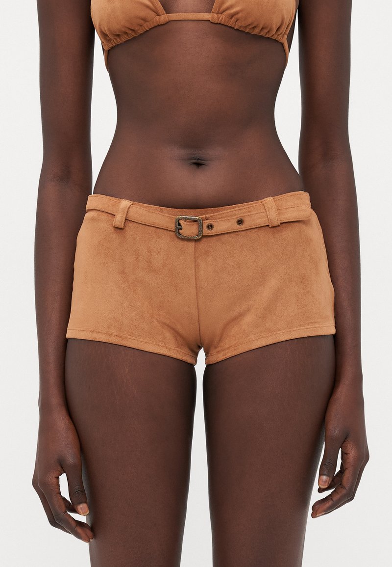 Bermuda in suede marrone con vita alta e cintura, caratterizzati da una finitura testurizzata e un design minimalista, che mettono in risalto linee pulite e una vestibilità sartoriale.