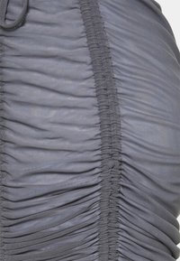 Tissu gris à texture froncée, présentant un design froncé et des coutures contrastantes le long des coutures. Matière douce et légère.