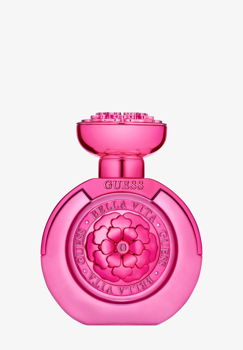 Ljusrosa Guess Bella Vita parfymflaska med blommig emblem och präglat varumärke mot en vit bakgrund.