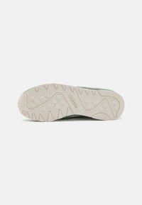 Green sneaker featuring a textured fabric upper, a padded collar, and a patterned rubber sole with traction grips.