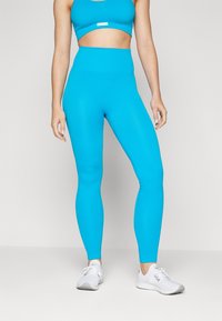 Lyse blå ribbede leggings med høy midje, paret med en matchende cropped topp. Stoffet har en glatt tekstur som fremhever passformen.