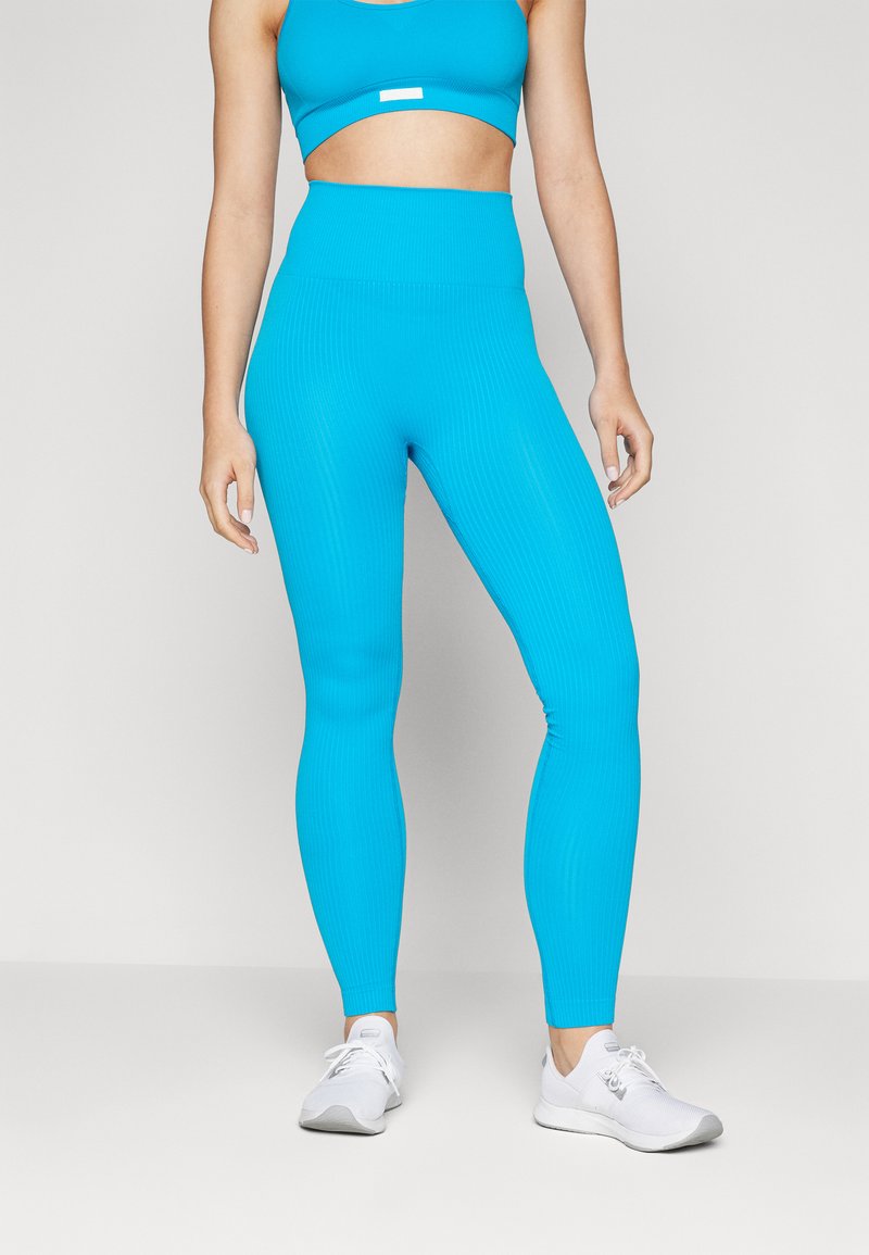 Lyse blå ribbede leggings med høy midje, paret med en matchende cropped topp. Stoffet har en glatt tekstur som fremhever passformen.