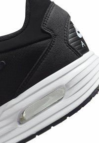 Zapatilla deportiva negra con un upper texturizado, media suela blanca y detalle de amortiguación de aire transparente. Presenta un logotipo en el talón y un diseño elegante.