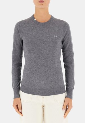 Maglione grigio a maglia con maniche lunghe, scollo e orlo a costine, caratterizzato da un piccolo logo bianco sul lato sinistro del petto. Texture liscia, design aderente.