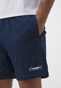 Granatowe szorty sportowe wykonane z mieszanki bawełny, z elastycznym pasem i wyraźnym białym logo "hummel sportswear".