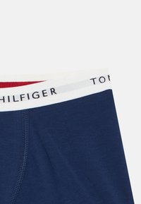 Σκούρα μπλε μποξεράκια με άσπλη ελαστική μέση που φέρει κόκκινες λεπτομέρειες κα ι το λογότυπο "TOMMY HILFIGER" σε μαύρα γράμματα.
