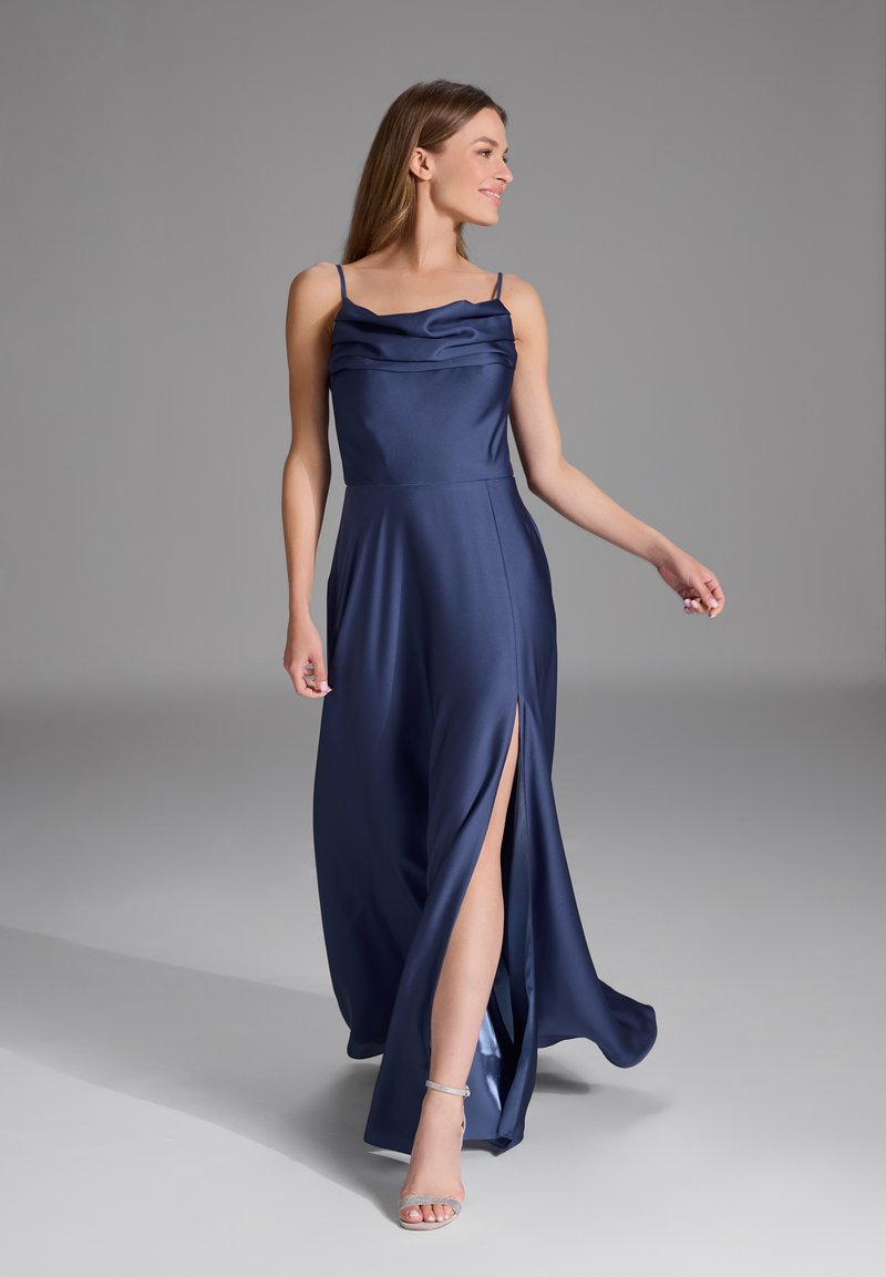 Robe en satin bleu marine avec un décolleté drapé, des fines bretelles et une fente haute sur la cuisse. Silhouette fluide avec une texture lisse et un design élégant.