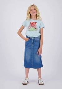 Šviesiai mėlynas trumpomis rankovėmis marškinėlis su grafiniu atspaudu; aukštos liemens džinsinė sijonas; kasdieniai balti sportbačiai su juodais akcentais; laisvas siluetas.