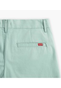 Lichtgroene katoenen broek met een gladde textuur, voorzien van een achterzak en een rood Levi's logo label dat is gestikt.