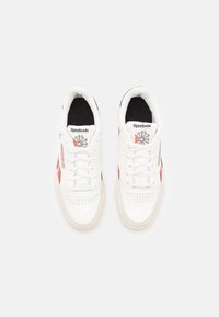 Vita lädersneakers med perforerad tåbox, röda accenter och svart innerfoder. Har klassisk Reebok-logga på tungan.