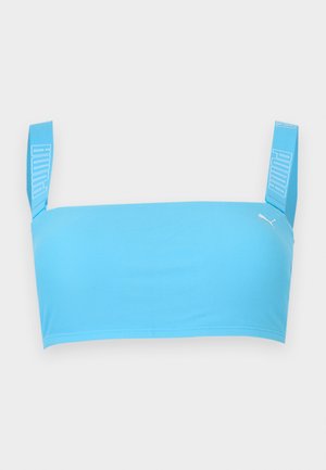 Ανοιχτό μπλε αθλητικό κοντό τοπ με φαρδιές τιράντες που διαθέτουν λευκά λογότυπα Puma και ένα μικρό λευκό λογότυπο γάτας Puma μπροστά.