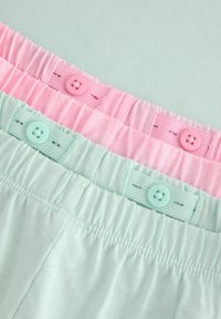 Drie paar elastische shorts in pastelkleuren: mintgroen, lichtroze en lichtblauw. Elk paar heeft een bijpassende knoop en een gestructureerde tailleband.