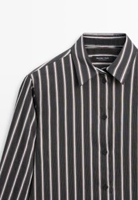 Schwarz-weiß gestreifte Bluse mit kontrastierenden roten Akzenten, klassischem Kragen, Knopfverschluss und strukturiertem Stoff. Markenetikett sichtbar.