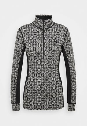 Langermet, kvart-zip topp med et svart og hvitt geometrisk mønster. Har kontrast svarte sidepaneler og mykt, teksturert stoff.