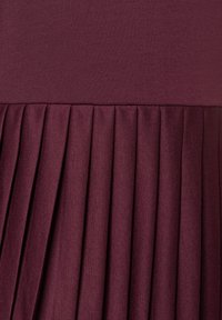Bordeaux plooiend kleedstof met een zachte bovenkant en textuur, gegatherde plooien bij de taille. Zacht, rekbaar materiaal.