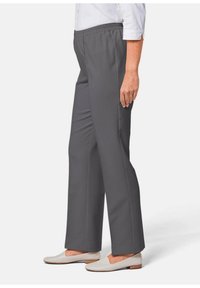 Pantaloni con elastico in vita grigi a gamba dritta, realizzati in tessuto liscio e senza tasche visibili, abbinati a scarpe slip-on di colore chiaro.