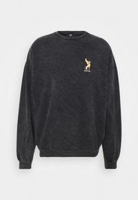 Sudadera gris oscuro con cuello redondo, mangas largas, puños y bajo acanalados. Presenta un pequeño gráfico de león dorado y texto en el pecho.