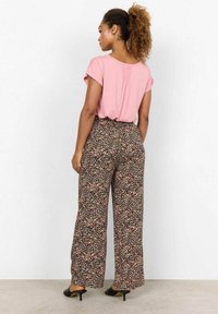 Růžový top s krátkými rukávy, se shubem na zádech, kombinovaný s širokými kalhotami černé barvy s květinovým vzorem, na kterých jsou malé vícerozměrné vzory a vysoký pas.