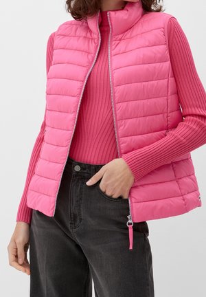 Roze gewatteerde vest met hoge kraag, gekenmerkt door verticale stiksels en een rits aan de voorkant. G gedragen over een bijpassende geribbelde trui en donkere broek.