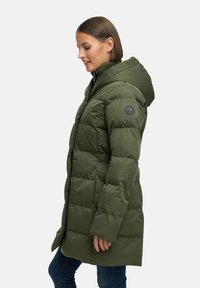 Pufjakas olīvzaļā krāsā ar lielu kapuci, izšūtu dizainu, priekšējiem pogām un apļveida logo uz piedurknes.