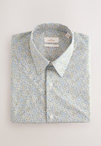 Camicia azzurro chiaro con motivo floreale giallo e blu, dotata di colletto classico e bottoni sul davanti, realizzata in morbido cotone.