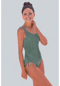 Maillot de bain une pièce en vert discret, avec des détails de liens ajustables sur les côtés, une texture lisse et de larges bretelles pour un bon maintien.