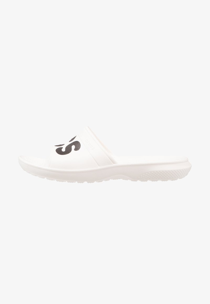 Sandale blanche à bout ouvert, de type slip-on, avec une semelle épaisse et un texte partiel noir en gras sur la bride du dessus.