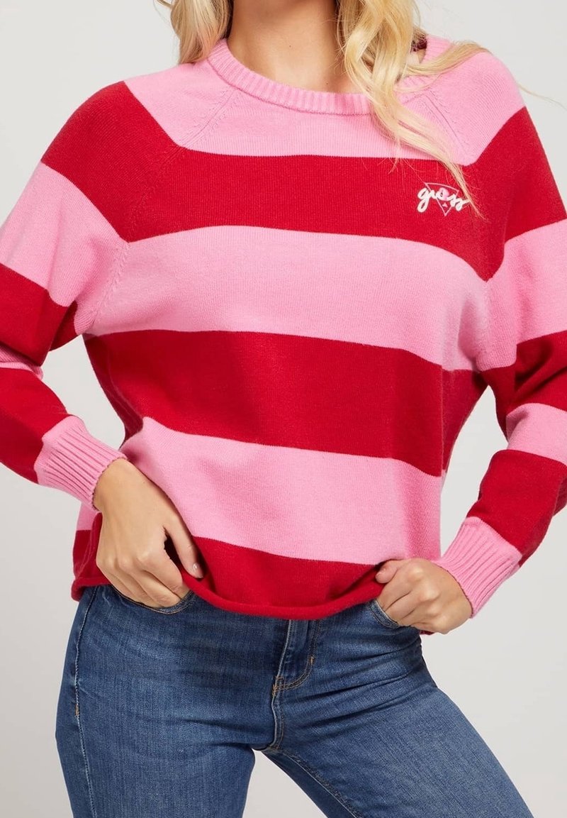 Pull rayé rouge et rose avec un col rond et des poignets côtelés. Présente un petit logo blanc sur la poitrine. Texture de tissu tricoté doux.