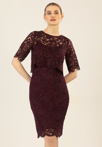 Burgunderfarbenes Spitzenkleid mit kurzen Ärmeln, taillierter Silhouette und geschwungenem Saum. Aufwendiges Blumenmuster über den gesamten Stoff.