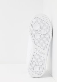 Weißer Sneaker mit strukturiertem Gummi-Sohle, die kreisförmige Muster zeigt, und "Kappa"-Branding. Glattes Obermaterial mit minimalistischer Gestaltung.