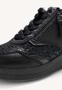 Sneaker noir avec un panneau latéral texturé et brillant, des lacets ronds et une fermeture éclair. La semelle est plate et en caoutchouc.