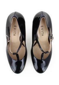Scarpe con tacco in vernice nera, con design a T-strap e finitura lucida; presentano una piccola fibbia in argento e un interno beige.