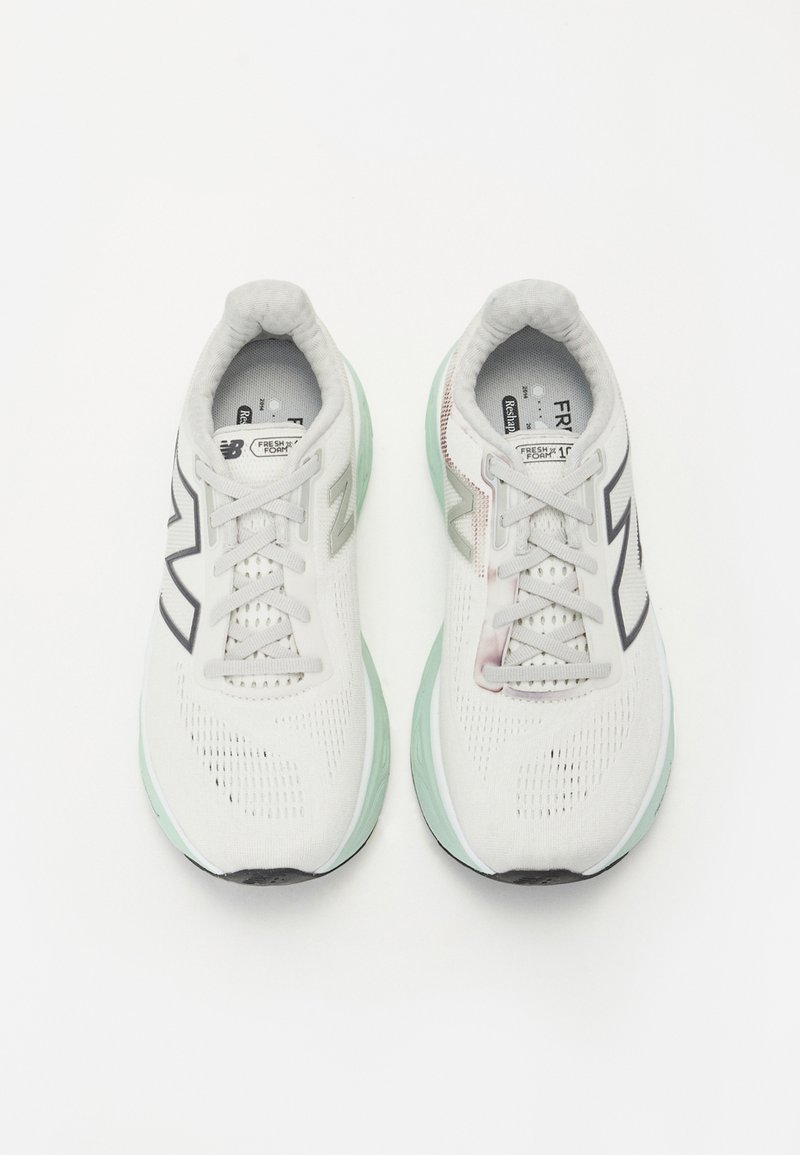 Zapatillas de running blancas con parte superior de malla, acentos en negro y gris claro, suela en verde menta y logo prominente en los lados. Diseño con cordones para un ajuste seguro.