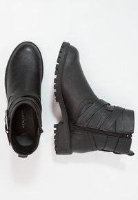 Botas negras de tobillo hechas de cuero liso con un diseño de pliegue texturizado, cremallera lateral y suela robusta.