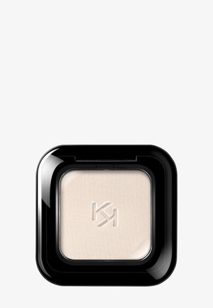 Ombre à paupières beige compacte carrée avec le logo "KM" en relief, encastrée dans un emballage en plastique noir brillant sur fond blanc.