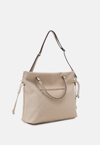 Sac à main beige matelassé avec deux poignées courtes, bandoulière longue amovible et poche zippée. Présente un matériau texturé et des accents en métal argenté.