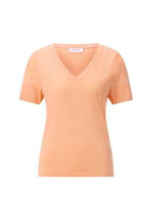 Ženska tunika breskvaste boje s V-izrezom i kratkim rukavima, nazubljenim rubovima rukava i oznakom marke na izrezu.