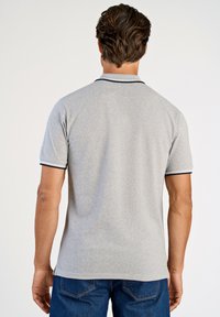 Grå pikétröja med en mjuk textur, med kontrasterande mörk krage och ärmsnibb, designad med rak nederkant och korta ärmar.