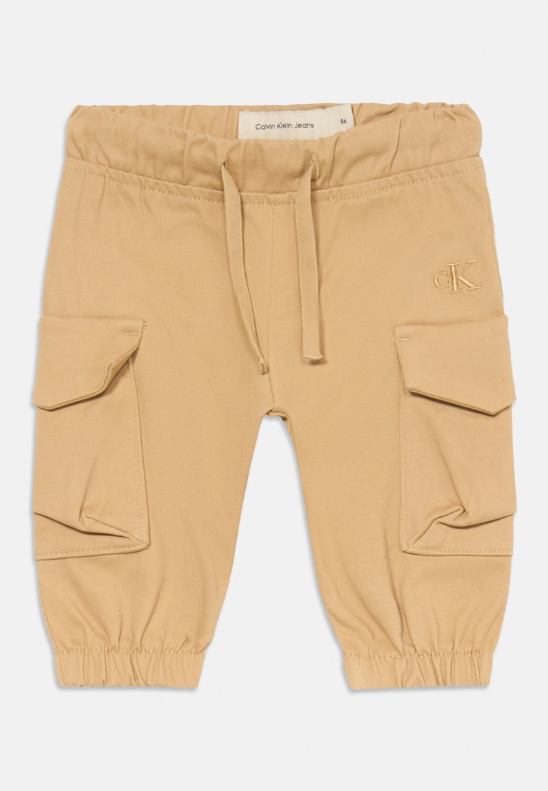 Kreminiai krovinių kelnės su elastinga juosmens juosta, raišteliu ir raibu kulkšnių kraštu. Yra dvi šoninės kišenės ir išsiuvinėtas Calvin Klein logotipas.