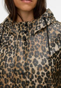 Imperméable à imprimé léopard avec capuche, présentant une finition brillante, des boutons pression noirs et des cordons de serrage ajustables.