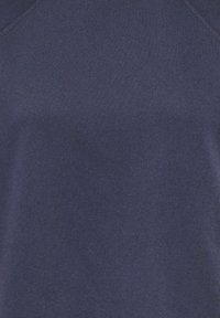 Gros plan sur un tissu bleu marine avec une texture tricotée visible, montrant un détail d'encolure en V.