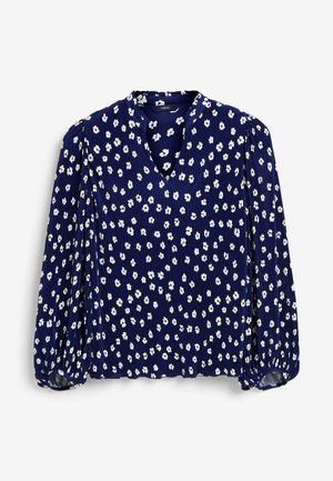 Blouse bleu marine à manches longues avec motif floral blanc, encolure en V, texture plissée et poignets froncés.