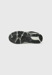 Semelle de chaussure de sport noire avec un motif de semelle multi-directionnel. Comprend des accents gris clair et une surface texturée pour une adhérence améliorée.