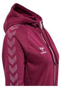 Bordeauxfarbener Reißverschluss-Hoodie mit Kapuze, weißem Chevron-Muster am linken Ärmel und kontrastierenden Reißverschlussdetails. Weicher Stoff mit tailliertem Design.