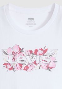 Λευκό βαμβακερό t-shirt με λουλουδένιο σχέδιο από ροζ και κόκκινα λουλούδια, με το λογότυπο «Levi's» σε έντονη γραμματοσειρά στο κέντρο.