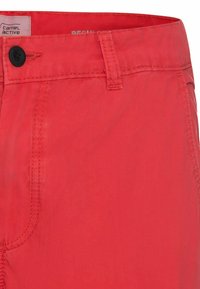 Shorts rouges en tissu léger, avec fermeture à boutons et coutures détaillées. Texture lisse avec un léger éclat, poche latérale visible.