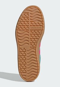 Grön och rosa sneaker sula med en texturerad gummifinish, med ett vågigt mönster och "adidas"-logotyp inbäddad i ytan.