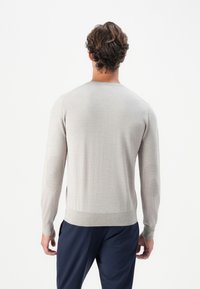 Helle graue Strickjacke mit langen Ärmeln, rundem Ausschnitt und gerippten Bündchen. Verfügt über Ellbogenflicken für zusätzliche Details und Textur.