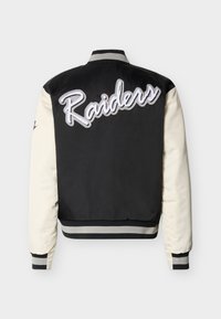 Μαύρο και κρεμ μπουφάν varsity με μεγάλο κεντημένο λογότυπο "Raiders" στην πλάτη, ριμπ γιακά και ριγέ μανσέτες. Λείο υφή.